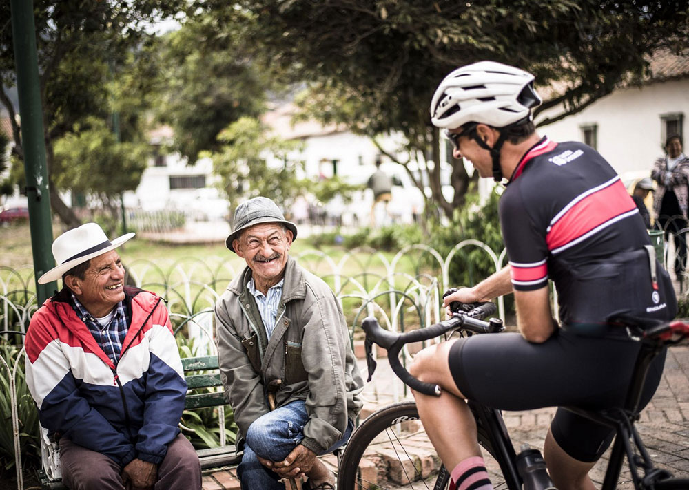 A cyclist chats to two smiling older men