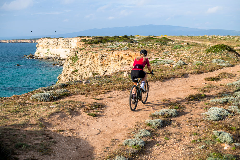 A woman cycles along the edge of a spectacular coastal cliff
