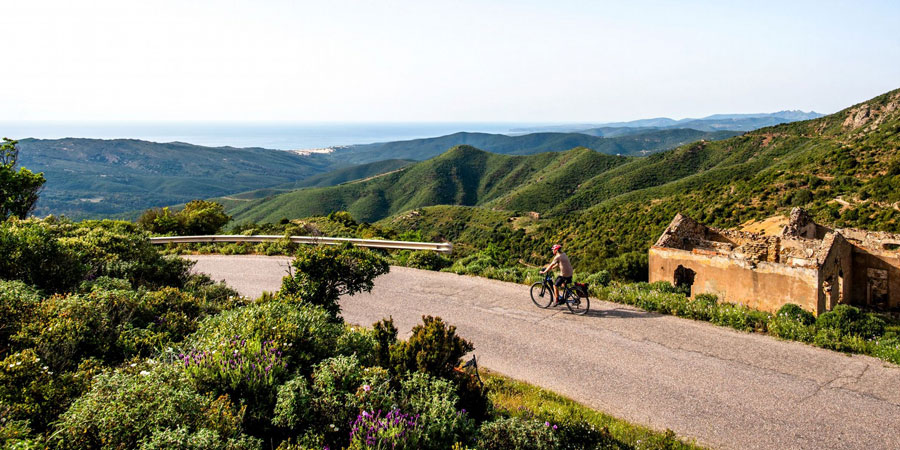 Someone on an e-bike cycles through mountainous Sardinian countryside