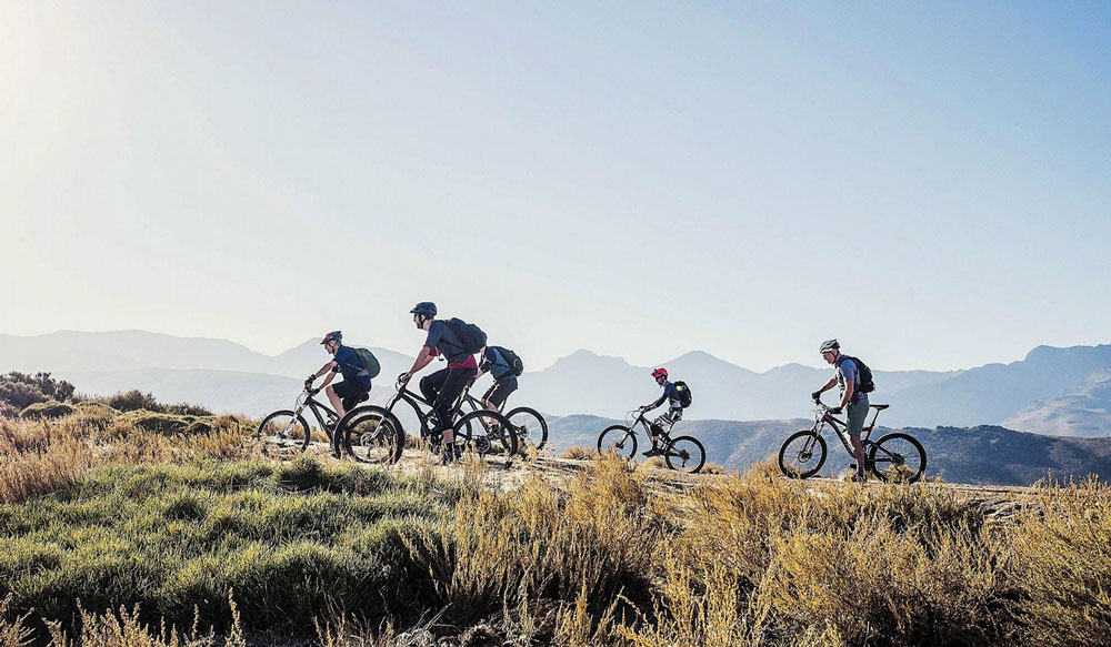 Mountain bikers ride against a backdrop of the sierra nevada