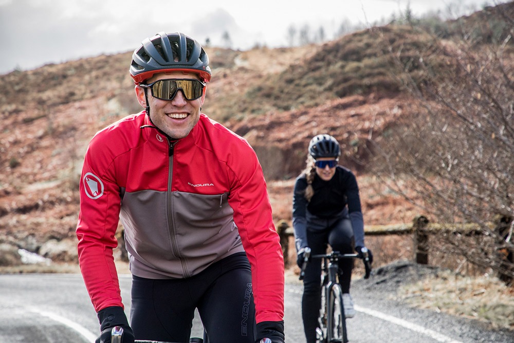 Two cyclists smile as they ride in cold weather