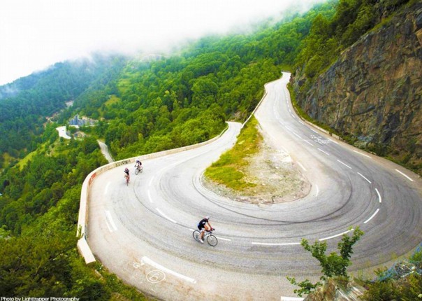 Three cyclists ascending the hairpin bends on the road to Alpe d'Huez in the French Alps
