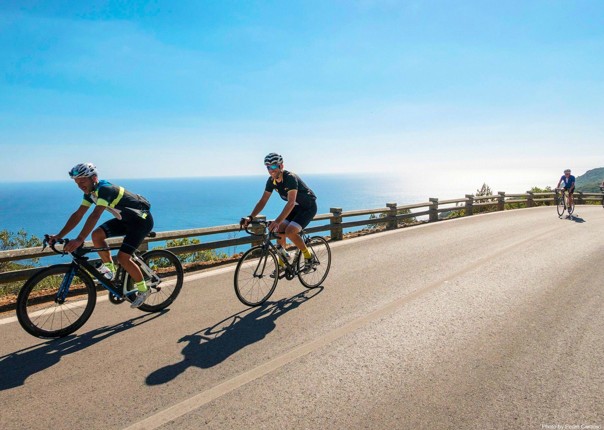 Group of road cyclists riding along a coastal road in Portugal on a guided tour