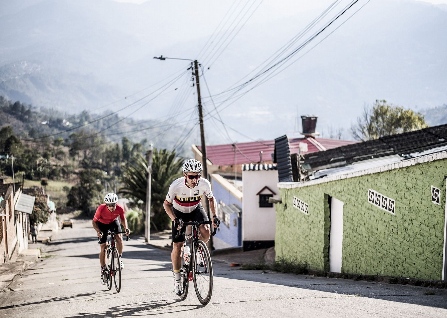 Two cyclists ascend a steep street in Colombia